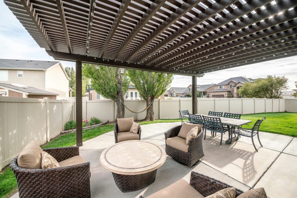 Woven armchairs with cushion and dining table under the pergola roof